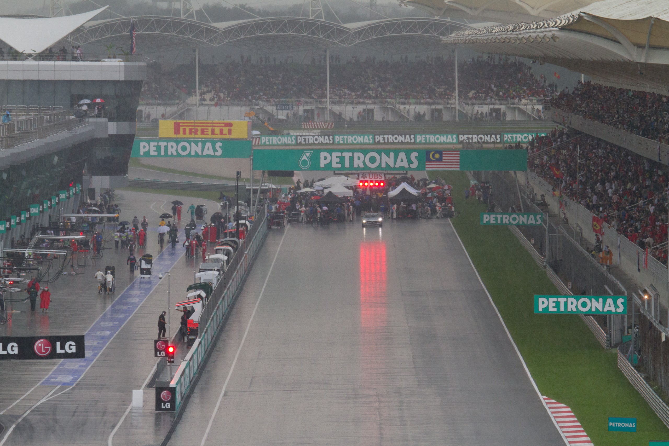 Formula 1 cars and the safety car wait on the suspended starting grid at Sepang during the rain-affected 2012 Malaysian Grand Prix